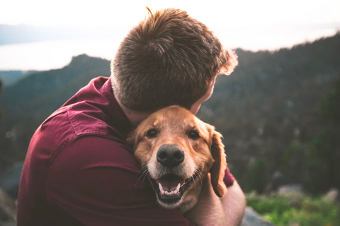 A man hugging his dog whilst out on a walk 