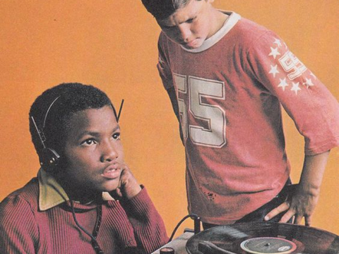 Two teenagers listen to a record together.