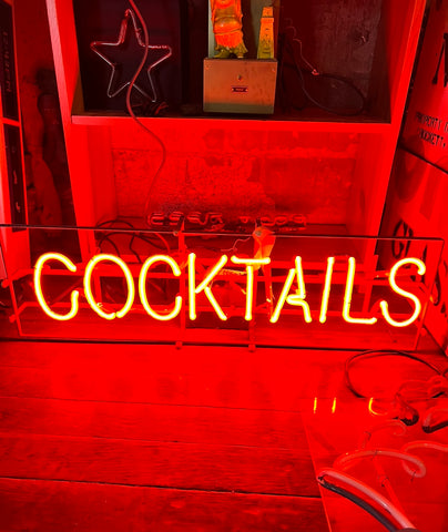 Vintage red neon sign that reads "COCKTAILS" in all capital letters