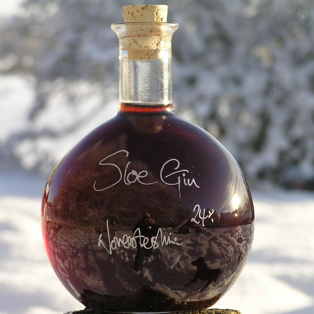 Round bottle of Sloe Gin in a snowy setting.
