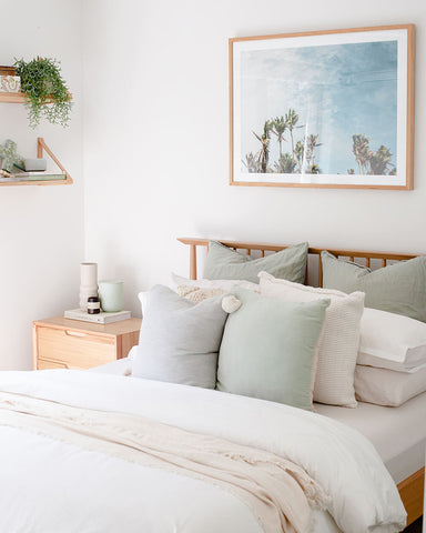 Coastal palm tree artwork in a bright bedroom styled with soft green decor accents