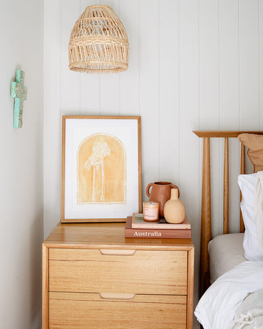 Golden palm rustic drawn artwork styled on a bedside table with a rattan pendant light and boho decor