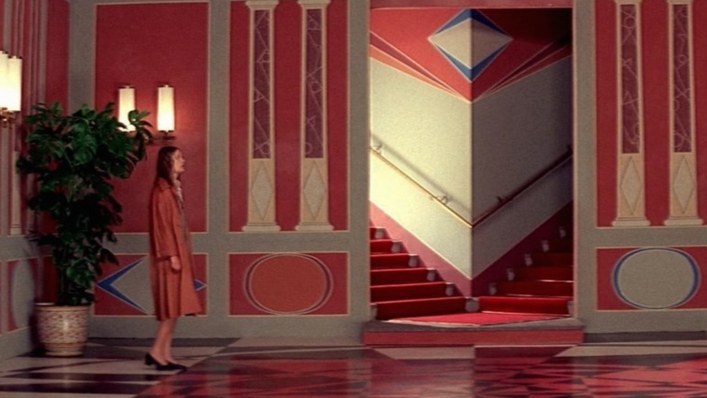 A woman stands in a confusing pink room.