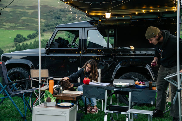 A couple enjoying cooking outdoors by their TentBox with their KitchenBox