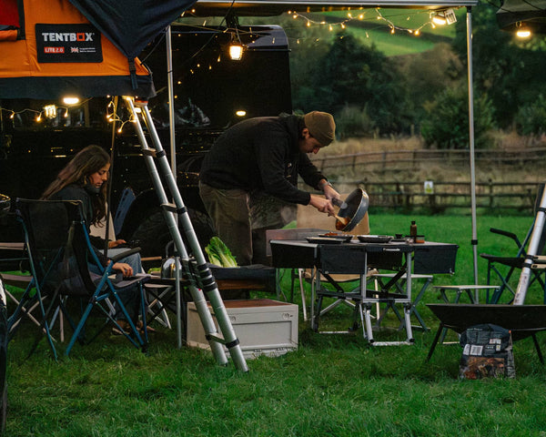 A couple cooking dinner in the outdoors using their KitchenBox