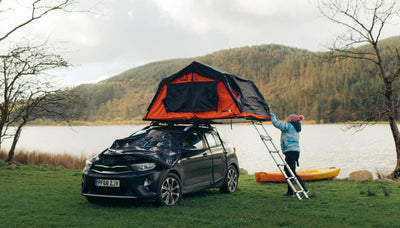 Woman standing near a TentBox Lite with her canoe, next to a lake