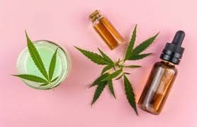 CBD cream and oils pictured over a pink background with cannabis leaves.