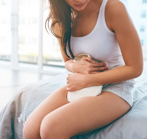 Woman holding a hot water bottle over her stomach for pain.