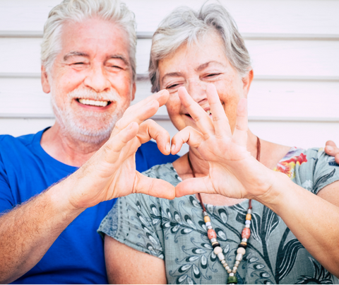 Elderly couple holding their hand together to form a heart.