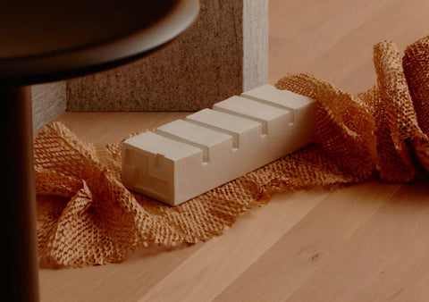 A ceramic sculpture in the shape of a block of apartments sits in paper styled on a wooden surface