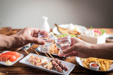 料理の前で日本酒を乾杯する人