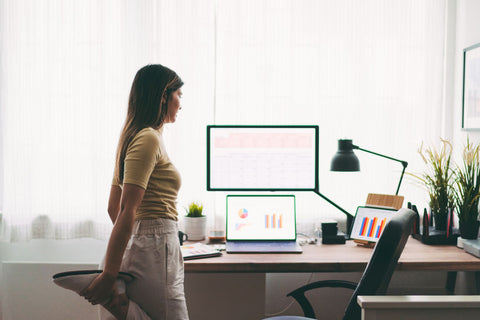 Woman stretching in home office during midday break