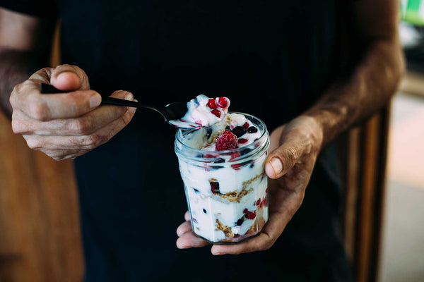 Man holding a jar of yogurt with berries and oats