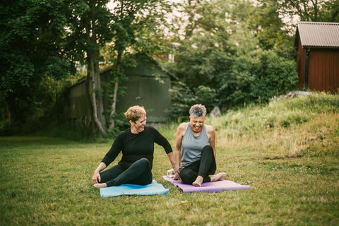 Two older women doing yoga outside