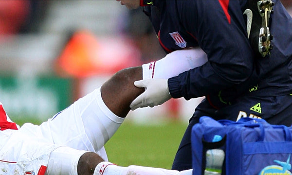 Physiotherapist treating professional football player's knee