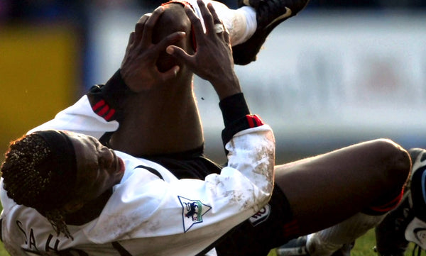 Professional football player holding his injured knee after fall