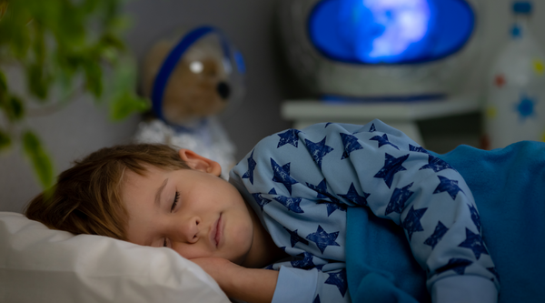 child is sleeping happily on his race car bed