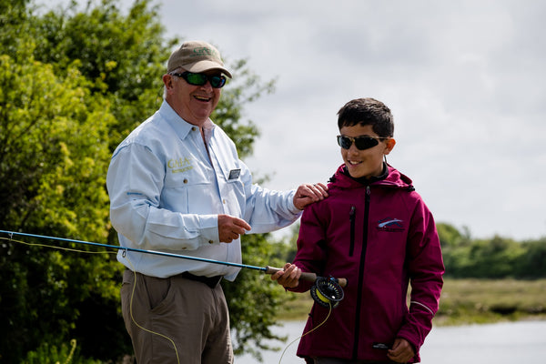 Angler and beginner hold a rod and smile