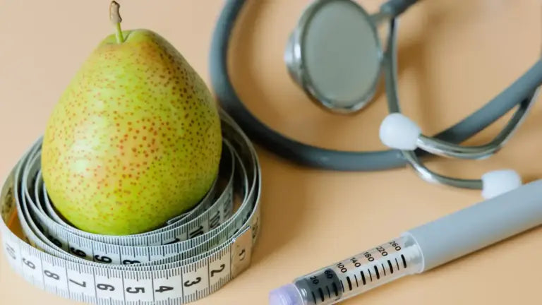 Green pear wrapped in a measuring tape beside a stethoscope and insulin syringe on a peach background, symbolizing natural strategies for blood sugar management and weight loss.