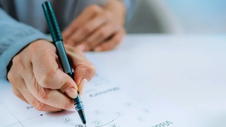 An elderly person’s hands holding a pen and filling in a crossword puzzle on a printed sheet, illustrating cognitive engagement and the brain health benefits linked to spermidine supplementation.