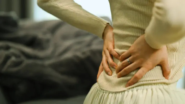 Close-up of a person pressing their hands into the small of their back, conveying tension and discomfort that apigenin’s calming, anti-inflammatory effects may help alleviate for better sleep and healthy aging.