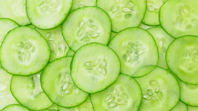 Overlapping thin rounds of fresh cucumber arranged in a close-up pattern, highlighting cucumbers as a natural source of NMN.