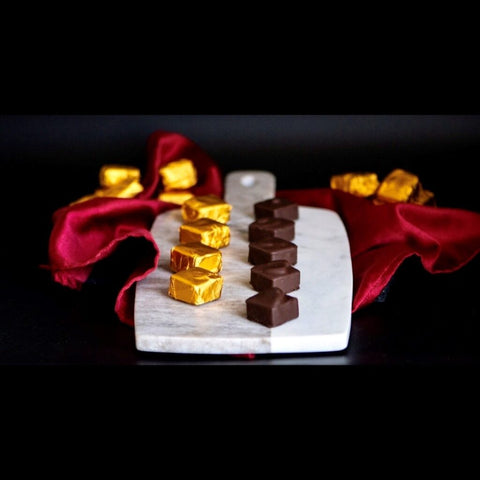 Chocolate truffles arranged over a marble charcuterie board and a red cloth.