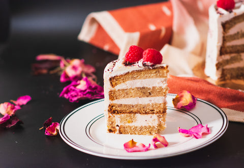 Slice of cake showing layers of cake and buttercream, topped with fresh raspberries.