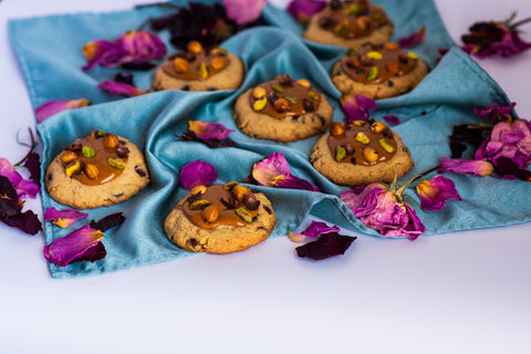 Image of chocolate chip cookies topped with praline, pistachio, and roasted hazelnuts.