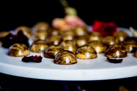 Golden-tinged chocolate bonbons arranged on a cake stand.