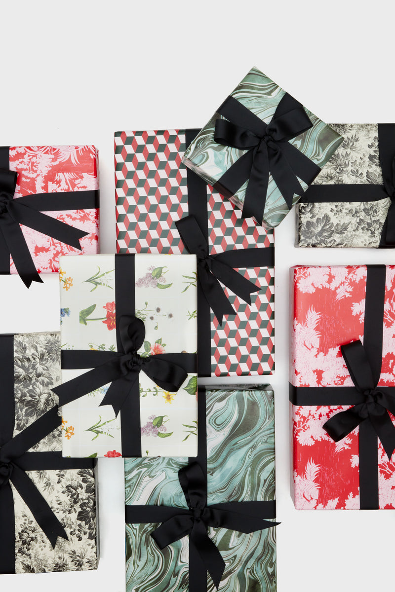 A collection of Supplies gift boxes wrapped in patterned paper with black ribbons, arranged on a white background.