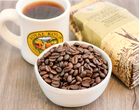 Brewed cup of Royal Kona Coffee with bowl of raw coffee beans