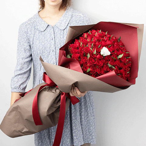 赤い薔薇の大きな花束を抱えた女性
