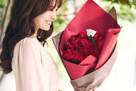 プロポーズでバラの花束を受け取り喜ぶ女性