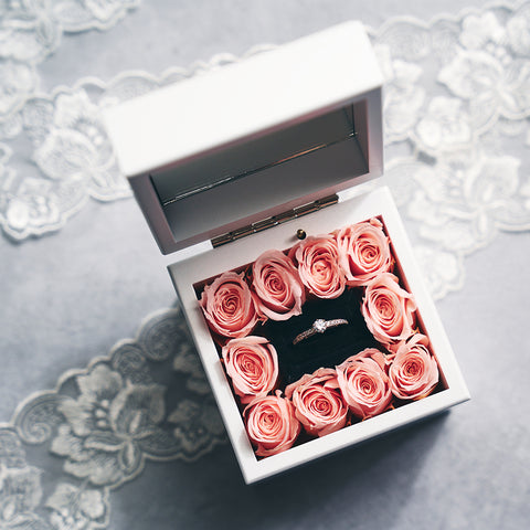 白い箱の中にプロポーズリングとリングを囲むようにピンクのバラを配置したアレンジ