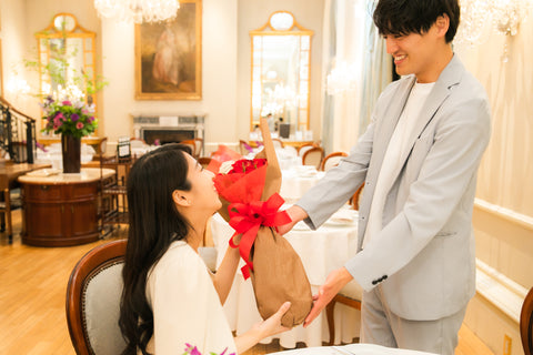 結婚記念日にレストランで赤い花束を贈る男性