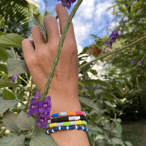 Love Is Project collaboration with Ocean Sole bracelets modeled in garden.