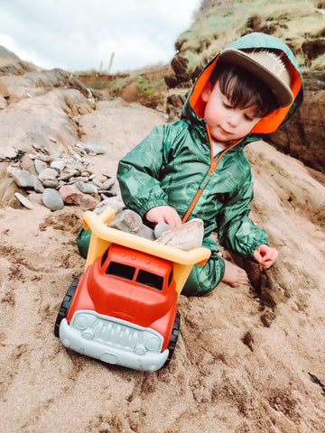 Boy playing with Red Dump Truck on the beach