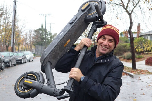 Man lifting the Segway Max electric scooter over shoulder