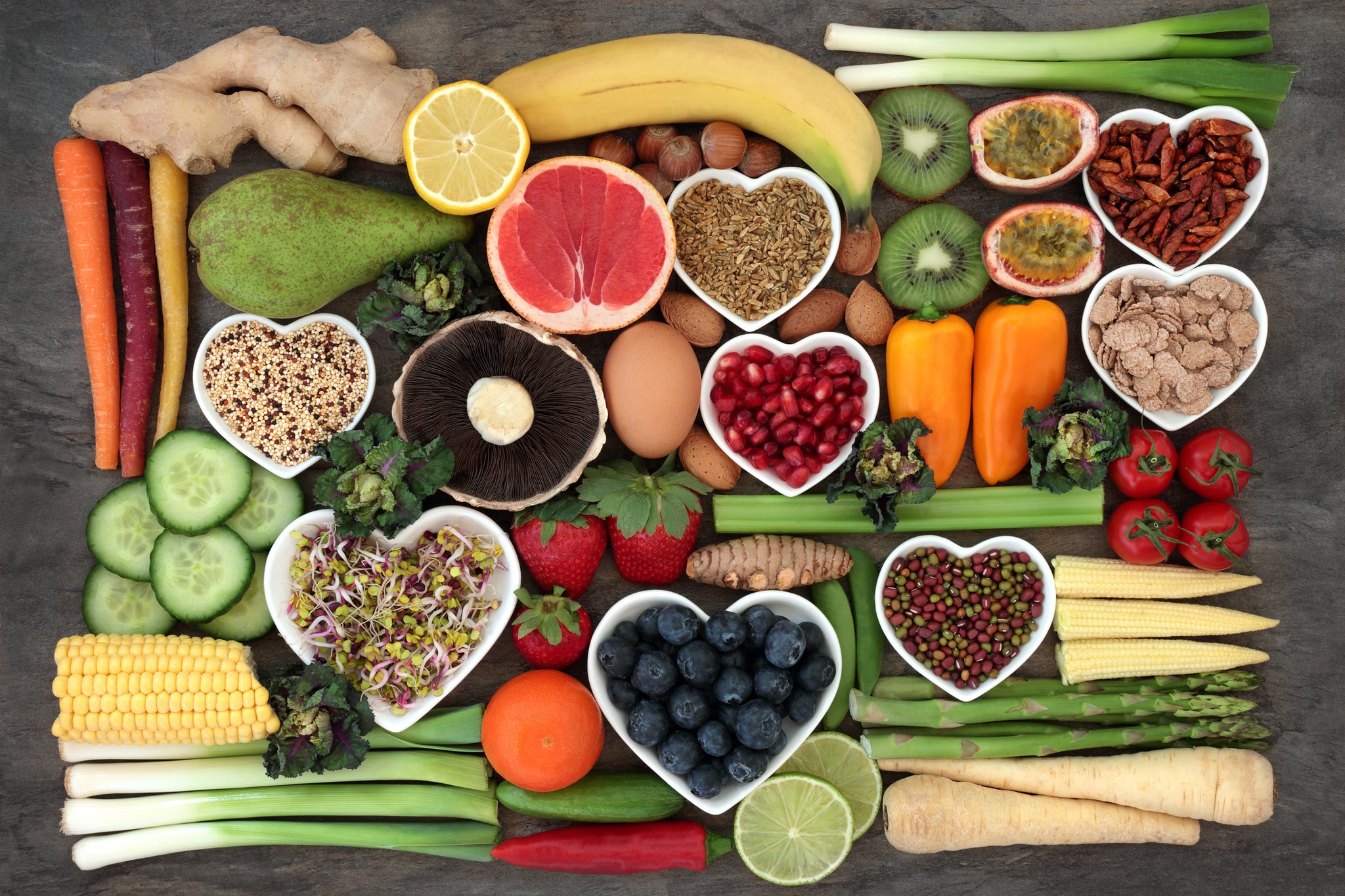 Various fruits and vegetables - some in heart shape bowls. 