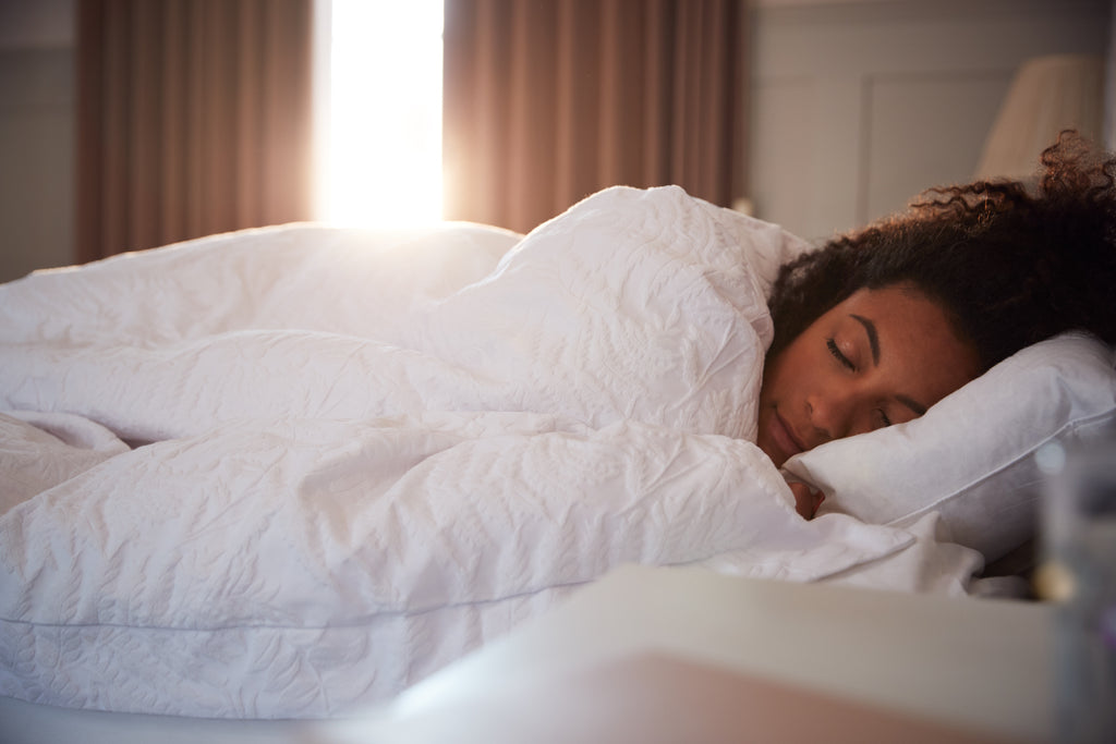 Woman sleeping in a hotel room.  All white linens. 