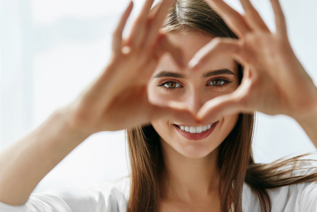 Woman holding heart hands in front of her face. 