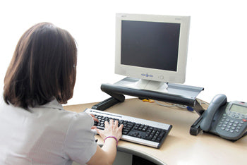 ergonomic single computer monitor stand holding a monitor at add level while the woman works at a desk