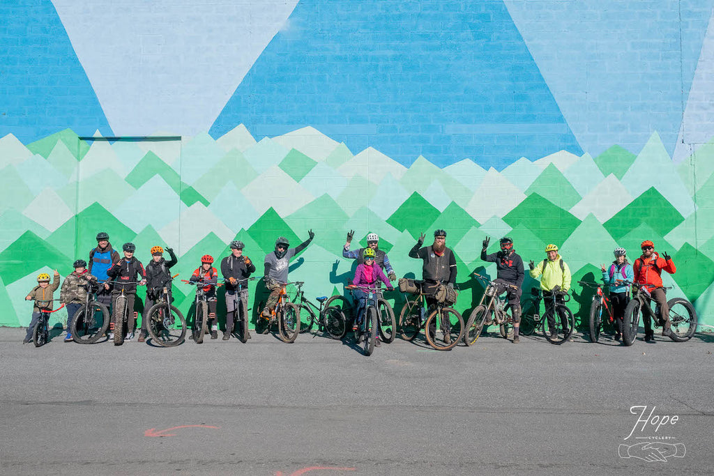 Group of bicyclists in front of mountain mural
