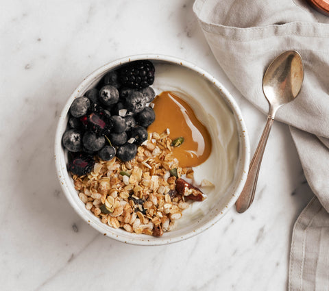 Bowl with granola, berries and protein power on marble background