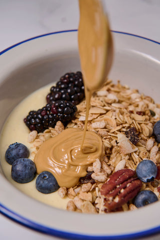 Bowl with yogurt, granola, blueberries and blackberries and peanut butter