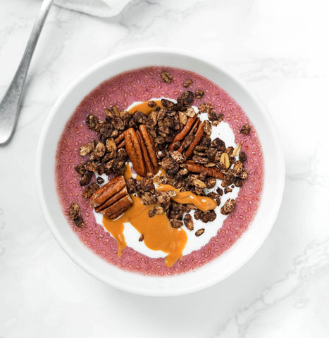 Strawberry chia pudding on white bowl with pecans and Chocolate Lover Granola