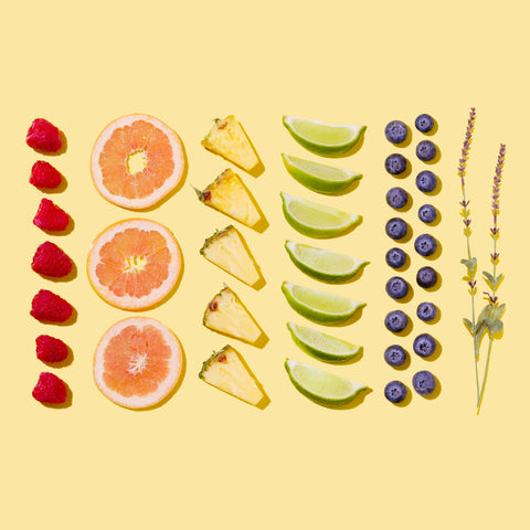 Cut lemons, pineapples, oranges, raspberries and blueberries on a yellow background