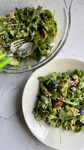 Ciotola e piatto con insalata con mirtilli, quinoa, noci pecan, cucchiaio e forchetta verde