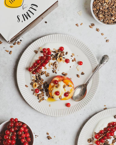 Plate with raspberries, chocolate lover granola, peach, teaspoon and box, bowl with raspberries